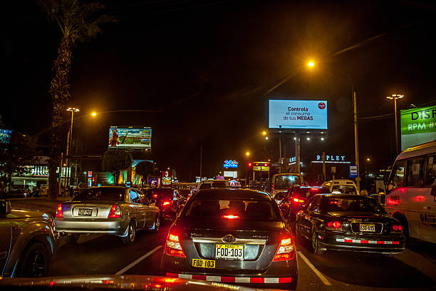Lima, Peru - January 8, 2015: City traffic in Lima at night. Drivers are visible in the cars and several illuminated advertising hoardings are also pictured
