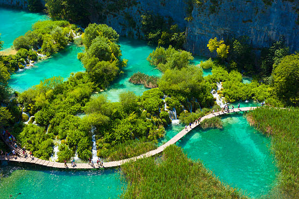 Plitvica Selo, Croatia - July 28, 2013: Tourists go on special tracks around the lake in the park Plitvice Lakes, Croatia. Plitvice Lakes - National Park in Croatia, located in the central part of the country. Since 1979, the national park \