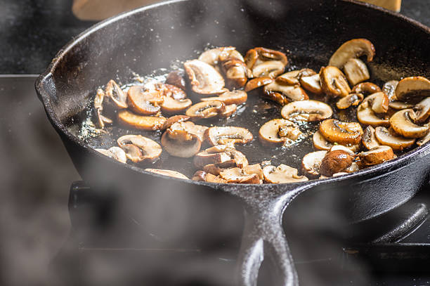 sauteing hongos en rodajas en una sartén plana - saute fotografías e imágenes de stock