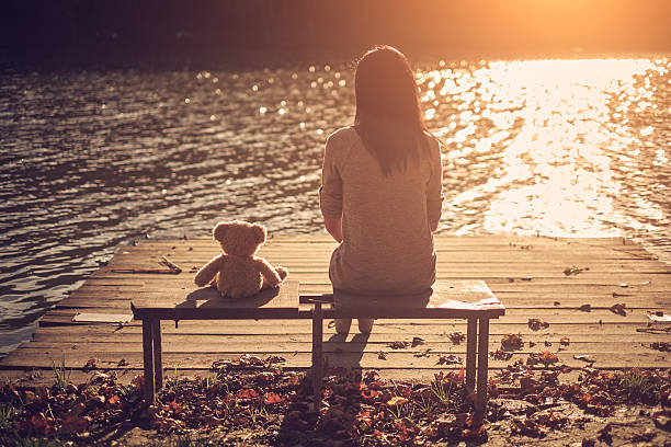 istock Woman and teddy bear sitting bench 537045935