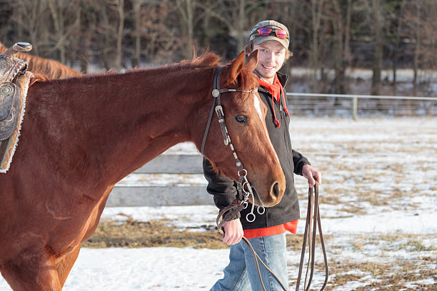 istock Young man walking saddled horse on snowy field 537061827