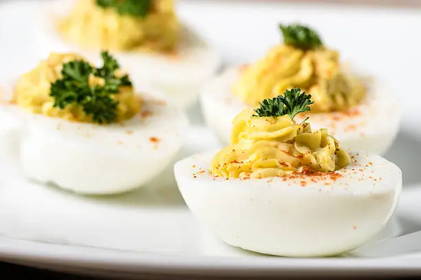 Piped and filled deviled eggs garnished with parsley and paprika