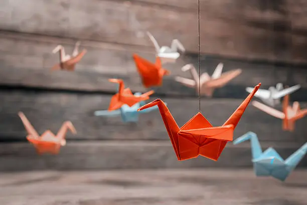 Colorful many origami paper cranes on wooden background