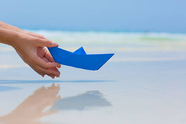 istock Female hand playing with paper boat on the beach 537075608