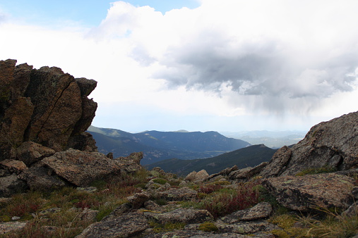 View from Mount Evans, CO summit, surrounded by large boulders framing the mountain range.