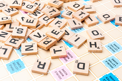 Miami, Florida, USA - June 22, 2014: Lettered wooden tiles mixed up on Scrabble game board. Scrabble is a fun and educational game distributed by Hasbro