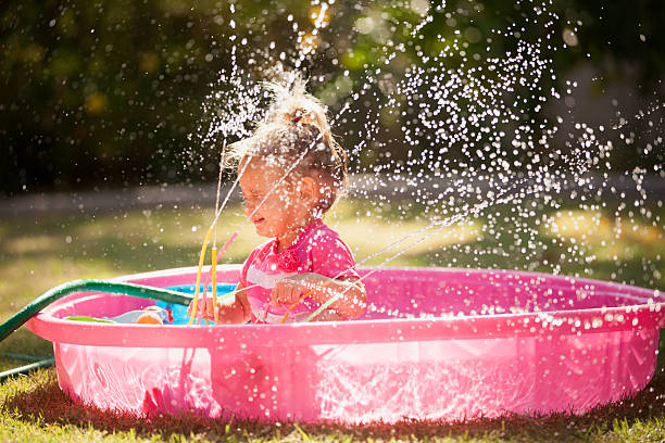 istock Little Girl Playing in Sprinkler 537097541