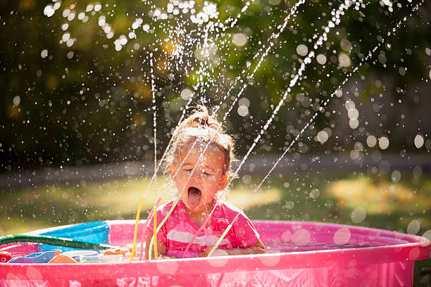 A young girl sitting poolside sticks out her tongue to show the blue color.