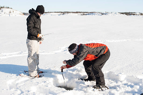 Couple Ice Fishing, Great Slave Lake, Yellowknife, Northwest Territories. Couple Ice Fishing, Great Slave Lake, Yellowknife, Northwest Territories. great slave lake stock pictures, royalty-free photos & images