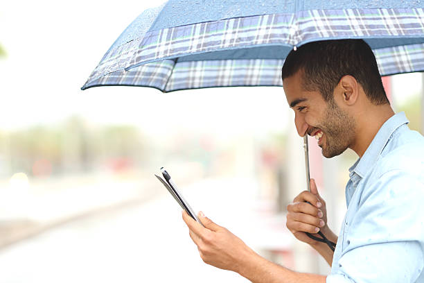 muslimischen mann lesung tablet-pc co. unter der regendusche regen - lesen regen stock-fotos und bilder