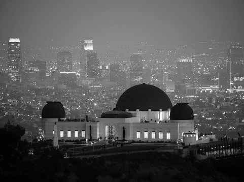 Foggy downtown night skyline behind Los Angeles's city owned Griffith Park Observatory.