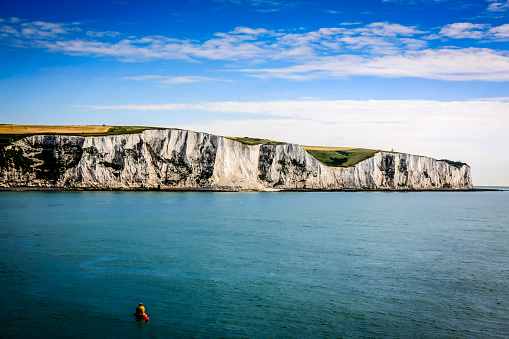 Dover, Kent, England - June 26, 2012: The White Cliffs of Dover, England are cliffs which form part of the English coastline facing the Strait of Dover and France. The cliffs have great symbolic value in Britain because they face towards Continental Europe across the narrowest part of the English Channel, where invasions have historically threatened and against which the cliffs form a symbolic guard.