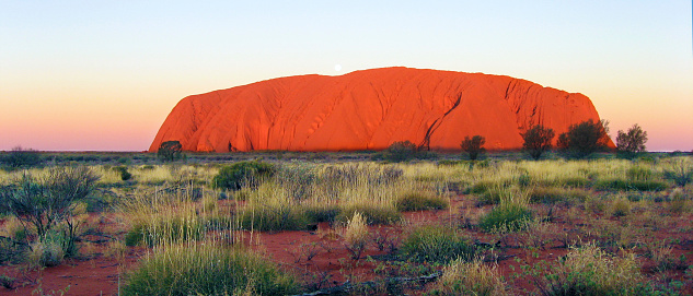Northern Territory, Australia - August 05, 2009: Evening descends on the Uluru-Kata Tjuta National Park, in the heart of Australia's Outback. The red rock reaches a vibrant orange.