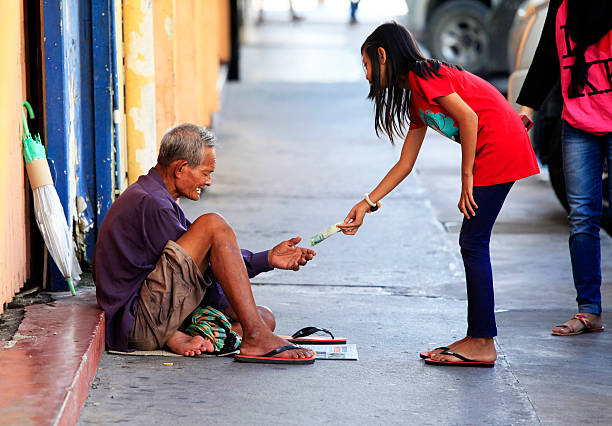 Homeless begger begging Kota Kinabalu, Malaysia - January 3, 2015: Young girl gives money to a beggar on the street Kota Kinabalu in Borneo, Malaysia ugly people crying stock pictures, royalty-free photos & images
