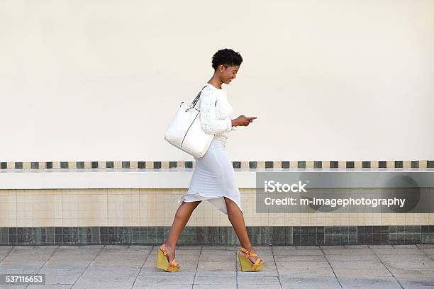 Photo libre de droit de Jeune Femme Marchant Et Lenvoi De Sms Sur Téléphone Portable banque d'images et plus d'images libres de droit de Marcher