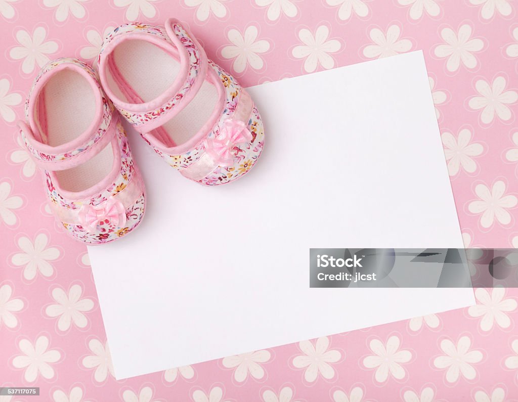 New baby announcement Blank card with baby girl shoes on a pastel pink floral background. It's A Girl Stock Photo
