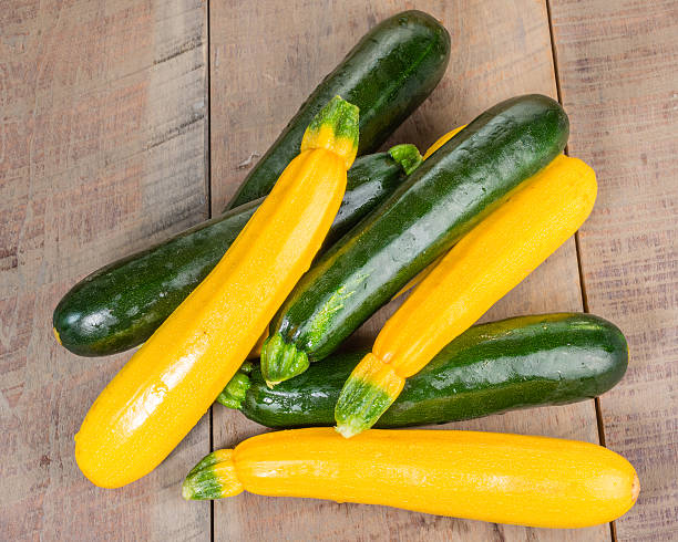 Zucchini and yellow squash on table Zucchini and yellow squash piled on a wooden table courgette stock pictures, royalty-free photos & images