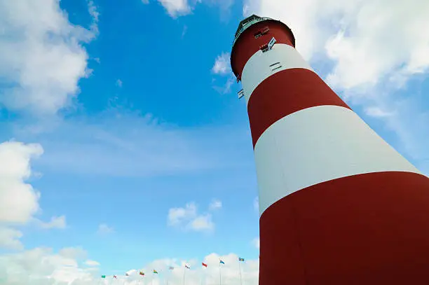 Lighthouse on Plymouth Hoe England constructed by John Smeaton in 1759 with national flags in foreground.