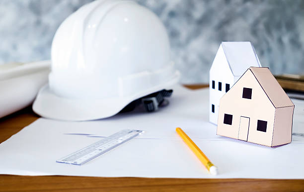 Construction engineering concept. Structural engineer and architect working desktop with safety helmet and paper model houses. Construction engineering concept. autocad house plans stock pictures, royalty-free photos & images