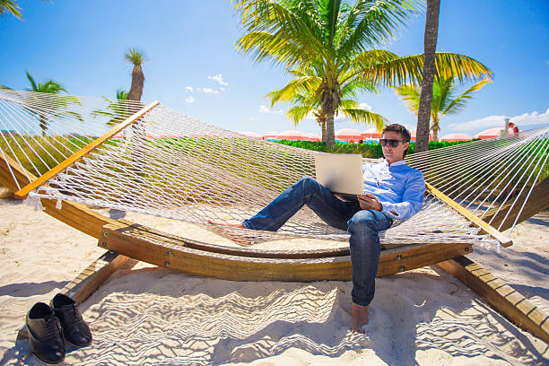 istock Young man working with laptop in hammock during beach vacation 537186409