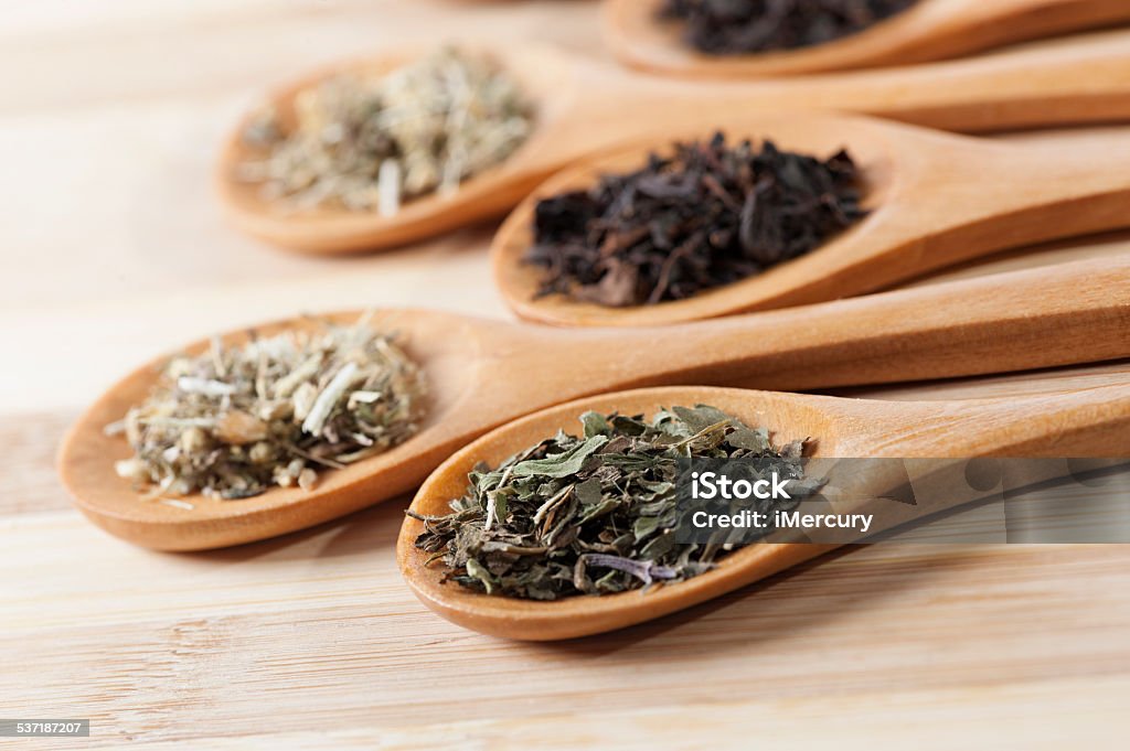 Dry tea on spoons Macro shoot, tea on a wooden spoon placed on a wooden table. Finely chopped tea served on a small wooden scoop. On picture you can see green, black and herbal tea. 2015 Stock Photo