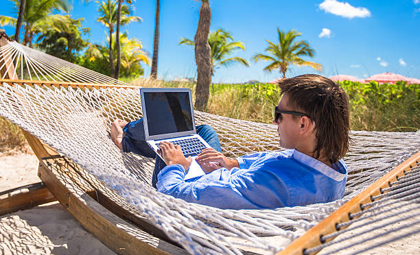 istock Young man working with laptop in hammock during beach vacation 537190765