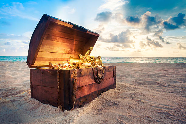Open treasure chest on the beach open treasure chest with shinny gold treasure chest photos stock pictures, royalty-free photos & images