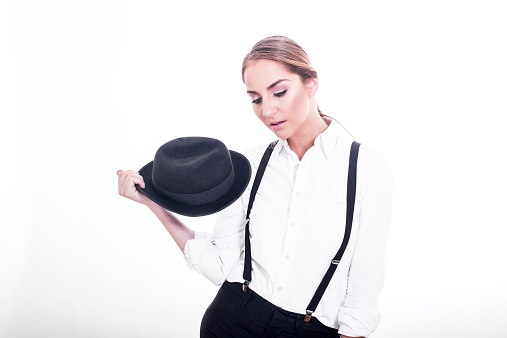 Portrait of beautiful young woman in man's  clothes with suspenders and hat