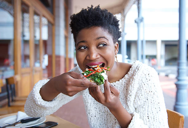 feliz jovem mulher comer pizza no restaurante - pizza eating african descent lunch imagens e fotografias de stock