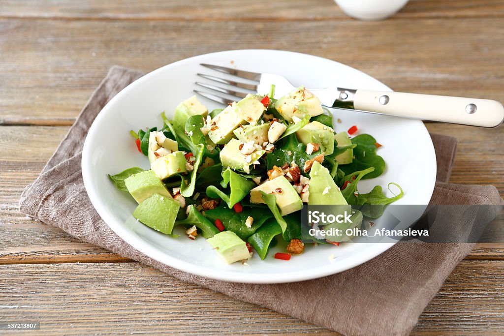 Salad with avocado, spinach and nuts in a bowl Salad with avocado, spinach and nuts in a bowl on a wooden boards 2015 Stock Photo