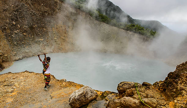 Touristic guide at the Boiling Lake Morne Trois Pitons National Park, Saint George Parish, Dominica - November 11, 2014: Hike guide in front of the Boiling Lake holding a walking stick above his head. fumarole photos stock pictures, royalty-free photos & images