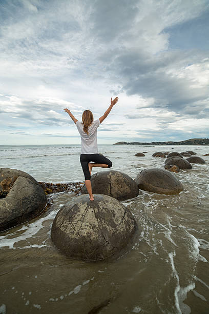 istock Cheering woman stands on spheric boulder by the sea 537232624