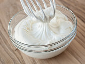 Whipped cream and whisk in glass bowl