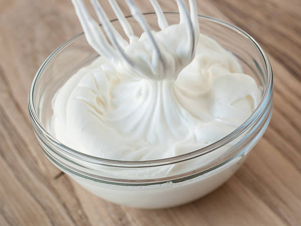 Whipped cream and whisk in glass bowl stock photo