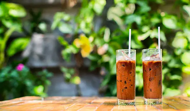 Photo of Two refreshing iced coffees in a warm summer garden cafe.