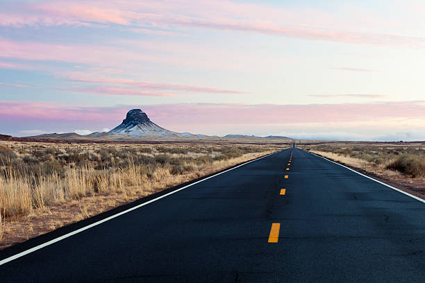 Open road near Winslow, Arizona at sunset.  Western United States landscape with grass and empty highway.  