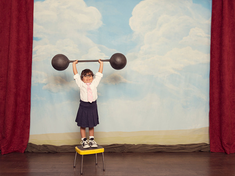A young girl businesswoman is ready to show her business savvy and strength by lifting weights that too heavy to lift by normal people.