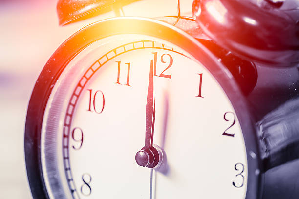 istock closeup vintage clock focus at 12 o'clock with sun light 537249302
