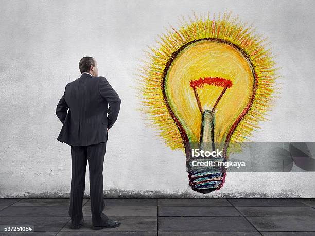 Businessman With Glowing Light Bulb Painting On The Wall Stock Photo - Download Image Now