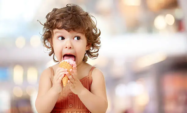 Photo of Kid eating ice cream. Funy curly child with icecream.