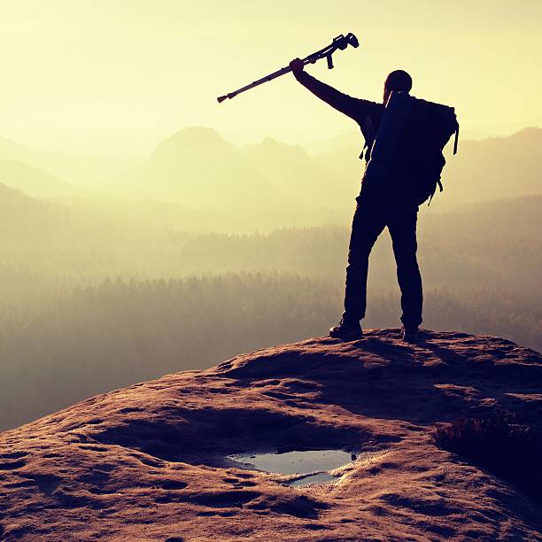 istock Hiker with crutch above head. Deep valley bellow man silhouette 537252730