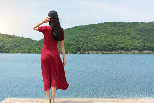 Fashionable woman standing in front of a lake alone