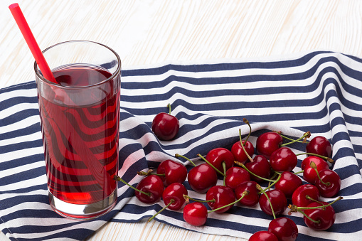 Juice and red cherries on wooden desk
