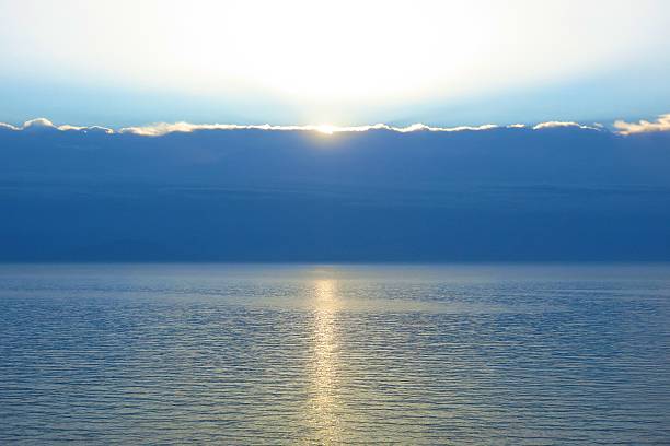 seascape sunbeam on sea with sun breaking over clouds on horizon stock photo