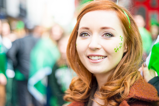 Smiling red haired Irish girl enjoying St. Patricks Day in Temple Bar, Dublin city, Ireland. 