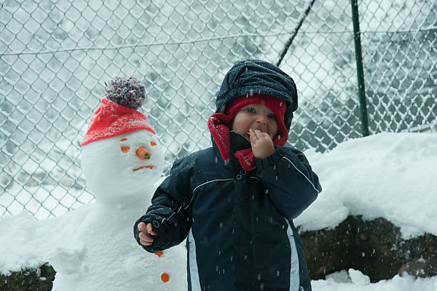 istock child in the snow with snowman 537269461