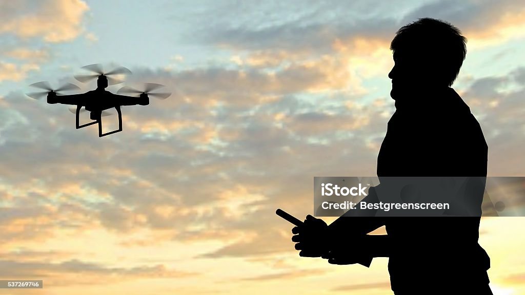 Hombre de funcionamiento de volador Soniquete quadrocopter al anochecer - Foto de stock de Dron libre de derechos