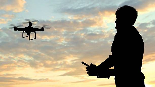 man operating of flying drone quadrocopter at sunset stock photo