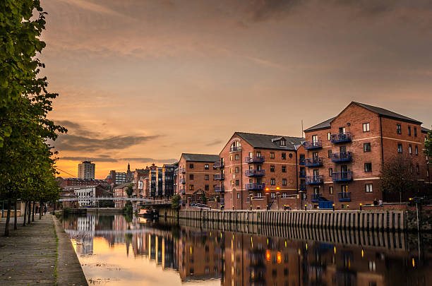Riverside Buildings at Sunset Renovated old buildings on the river Aire in Leeds at Sunset. Modern pedestrian bridge in background. leeds photos stock pictures, royalty-free photos & images