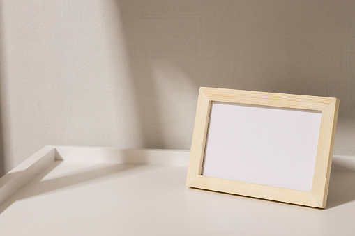 Decorating white shelf with blank wooden picture frame modern style.